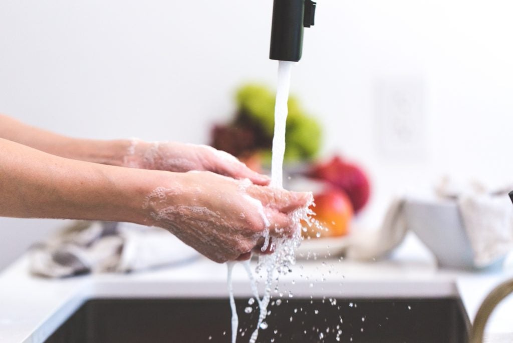 washing hands with soap and water with produce in the background