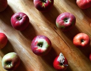Red and green apples laying on a wooden table