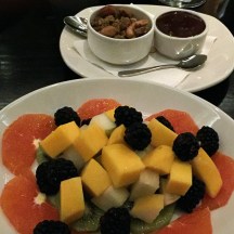 A platter of oranges, mangoes, blackberries, and kiwi, with nuts and chocolate