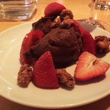 a scoop of dark chocolate ice cream with strawberries and almonds